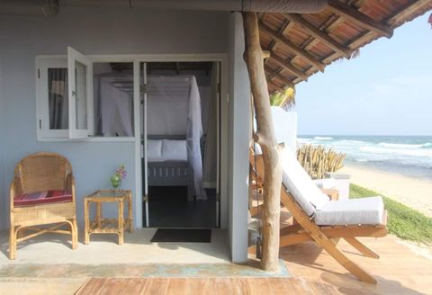 The open doorway of a room at EKA Beach opening onto the terrace and beach