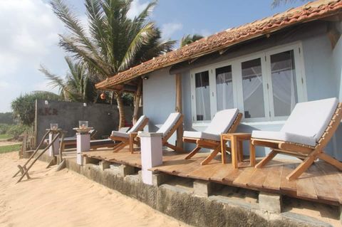 The white beachfront rooms of EKA Beach seen from the golden sand in Talpe, with loungers on the terrace and the sea beyond