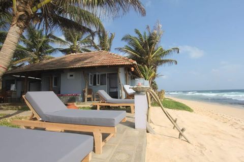 Timber loungers on the beachfront terrace at EKA Beach looking out to the sea