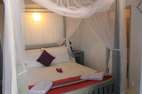 Queen bed under a white mosquito canopy in Room Two at EKA Beach