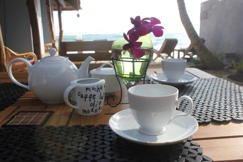 Tea, fruit and an orchid laid on a table at EKA Beach in Talpe