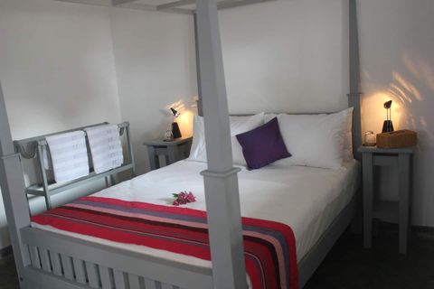 Four-poster queen bed with bedside lamps in Room Four at EKA Beach