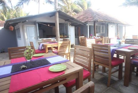 The shared breakfast terrace at EKA Beach, tables laid under the palms with the rooms behind