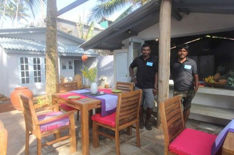 Breakfast being laid out on the terrace at EKA Beach, with fresh fruit on the table